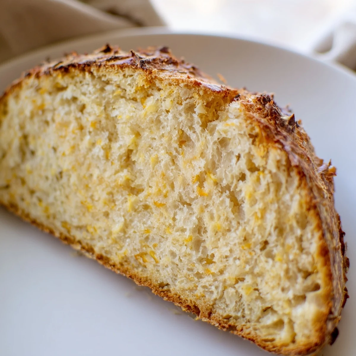 Freshly baked no knead cheddar bread cooling on wire rack with deep brown crust and airy texture