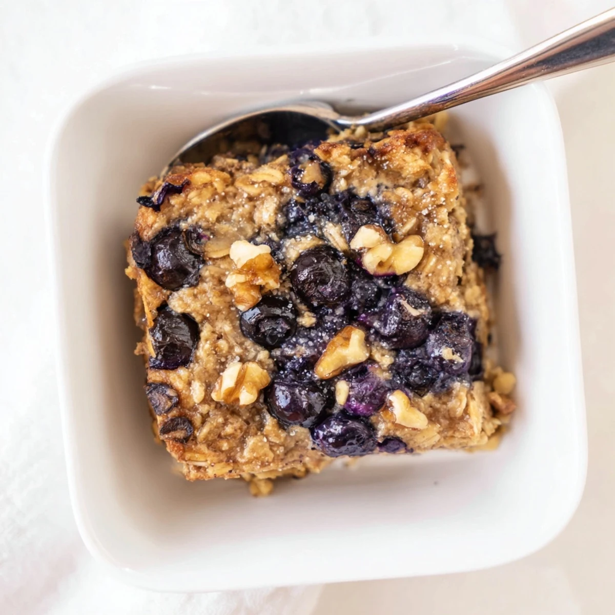 Wholesome lemon blueberry baked oatmeal squares topped with scattered blueberries and a dusting of sugar