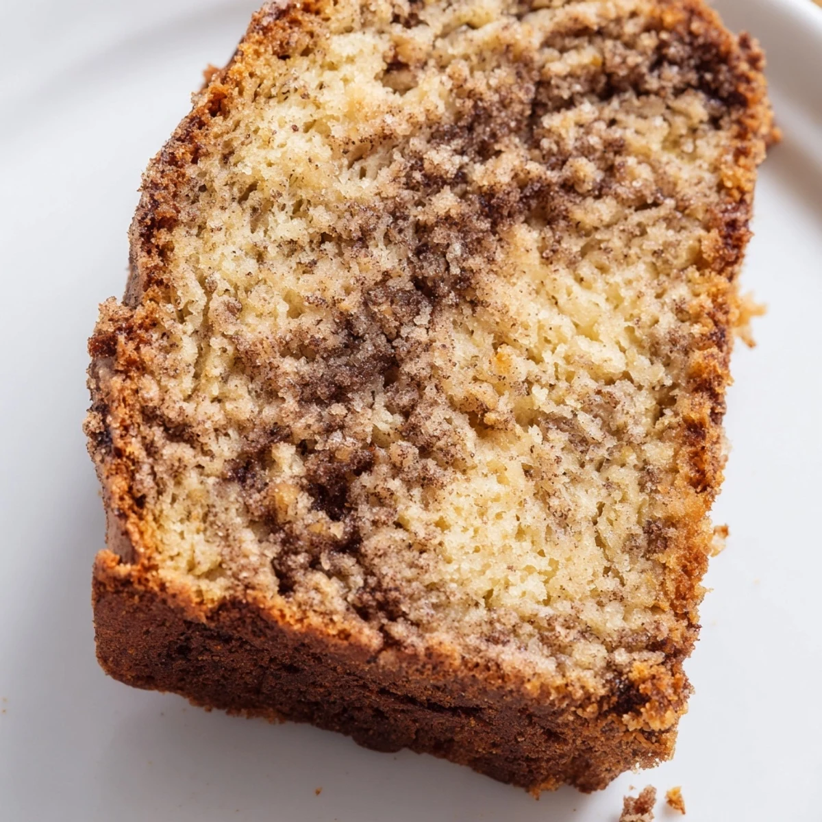 Fresh baked cinnamon sugar swirl banana bread displays caramelized swirled top on rustic wooden cutting board