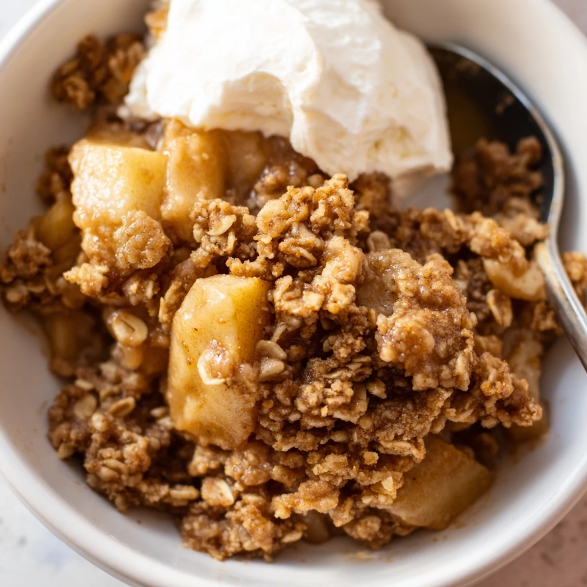 Crockpot apple crisp scooped into bowls and topped with melting vanilla ice cream