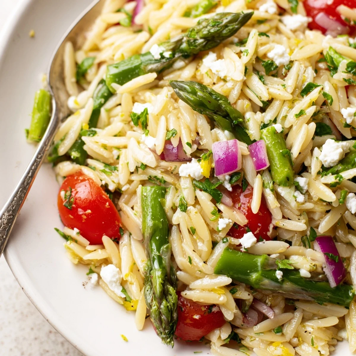 Zesty, chilled Asparagus Orzo Salad With Lemon Vinaigrette topped with crumbled feta