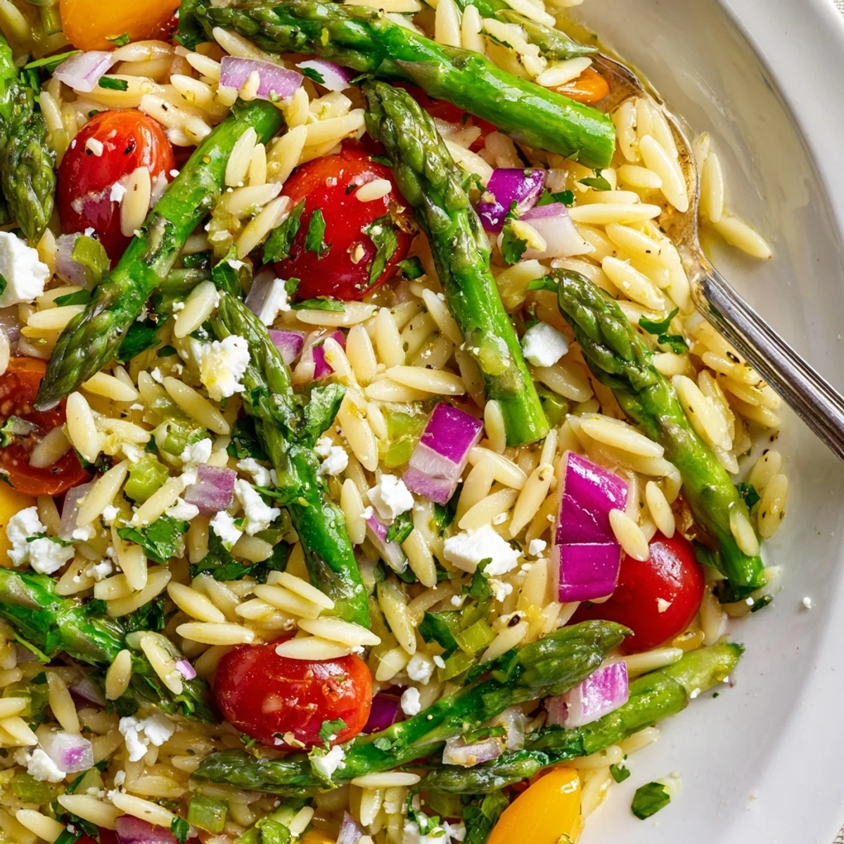 Forkful of bright Asparagus Orzo Salad With Lemon Vinaigrette showing juicy tomatoes