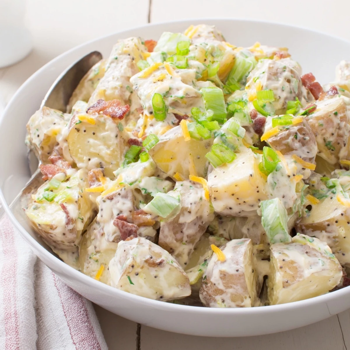 Hearty Beef Bacon Loaded Potato Salad piled in bowl, sharp cheddar melting