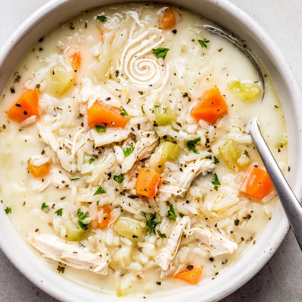 Creamy Chicken Rice Soup steaming in bowl, tender chicken and velvety broth.