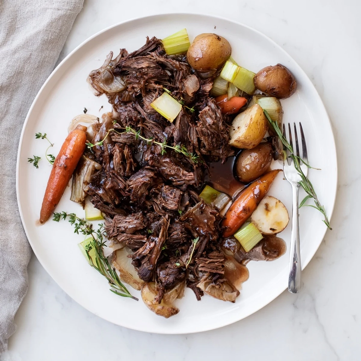 Golden seared beef chuck roast pot roast with carrots and herbs in Dutch oven