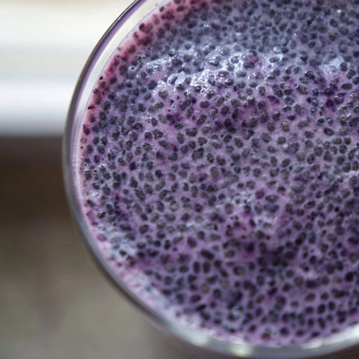 Thick purple chia seed smoothie topped with fresh berries in a clear glass