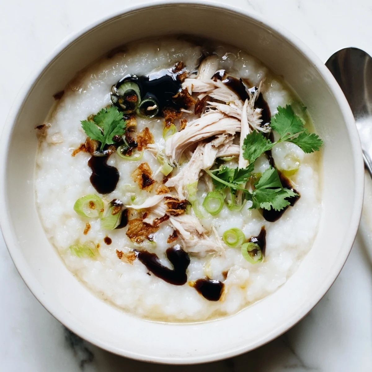 Creamy chicken congee topped with fresh scallions in a white ceramic bowl