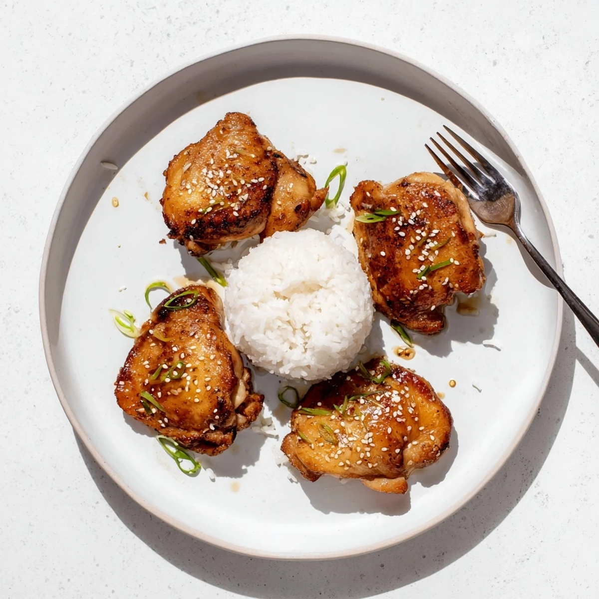 Tender Honey Garlic Chicken thighs glazed golden, sprinkled with sesame and green onions
