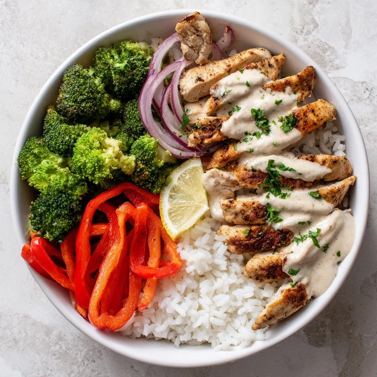 Family-style Grilled Chicken Broccoli Bowls with Creamy Garlic Sauce, charred chicken and lemon