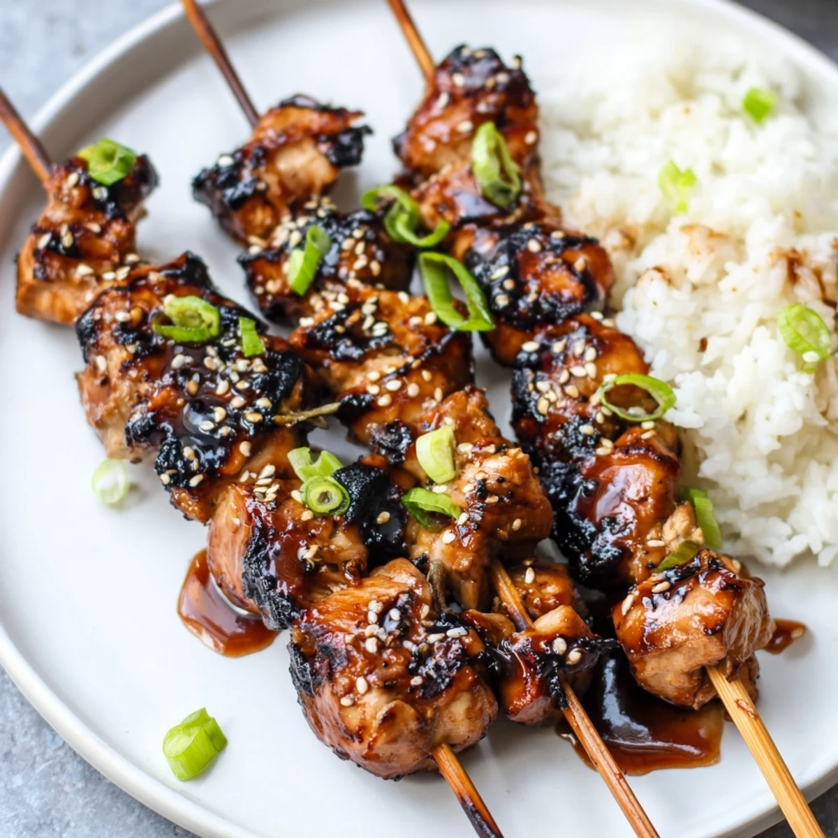 Teriyaki Chicken Skewers glistening with sticky glaze, charred edges, sesame garnish