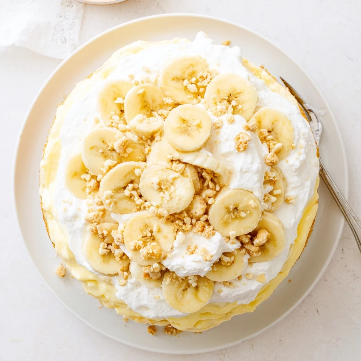 Golden banana pudding cake recipe layered with creamy vanilla filling and topped with fresh sliced bananas