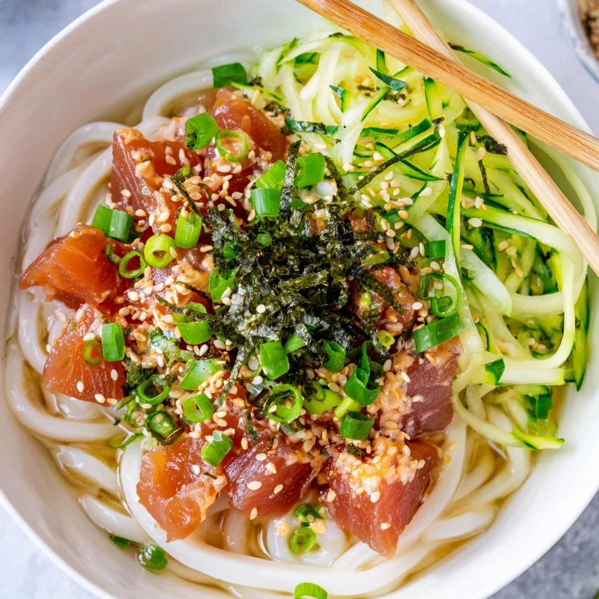 Japanese-style spicy tuna udon featuring marinated raw tuna over thick chewy noodles in savory dashi broth