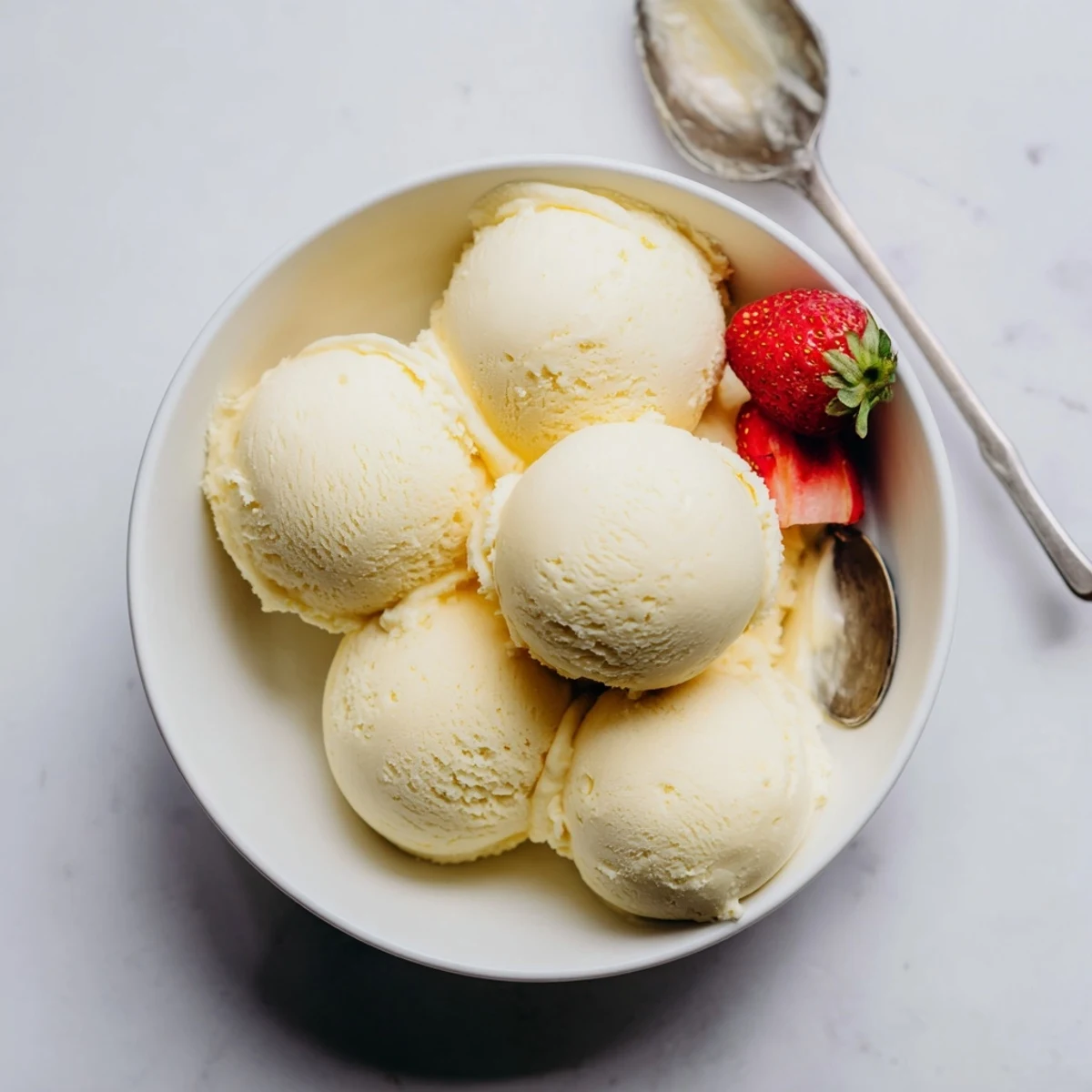 Creamy homemade vanilla ice cream scooped into a glass bowl with fresh berries