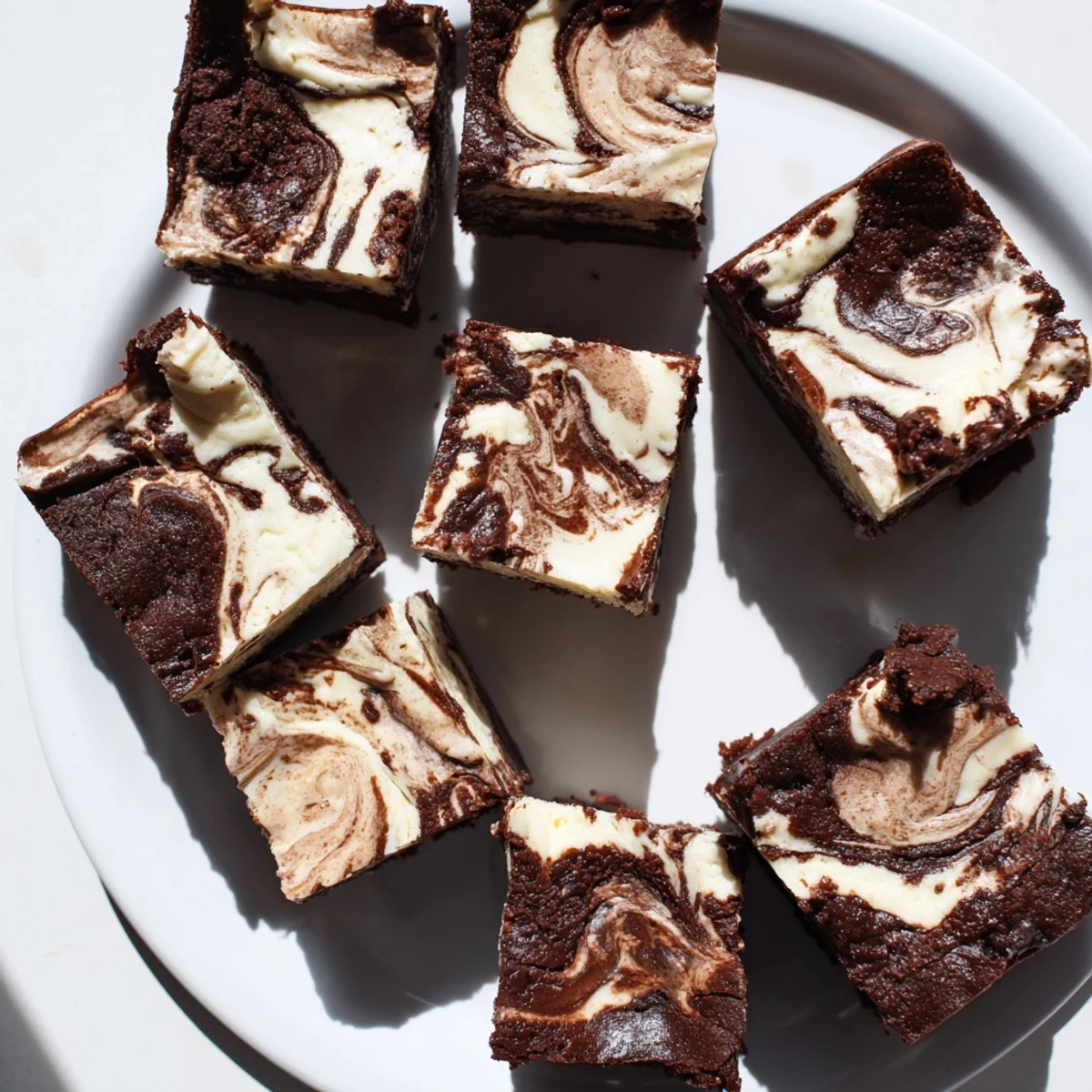 Golden brown sourdough brownie bars featuring marbled cheesecake topping on a white ceramic plate