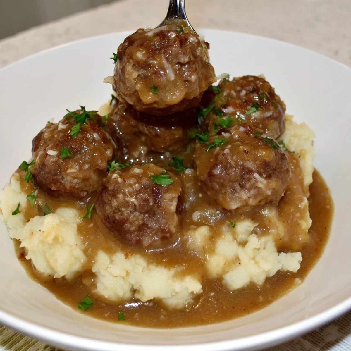 Creamy Crockpot Meatballs Gravy spooned over buttered egg noodles for family dinners.