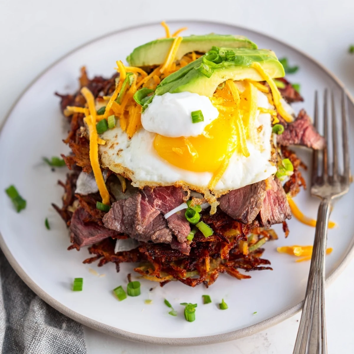 Loaded Steak Egg Hash Brown Stacks with crispy golden potatoes and melted cheddar