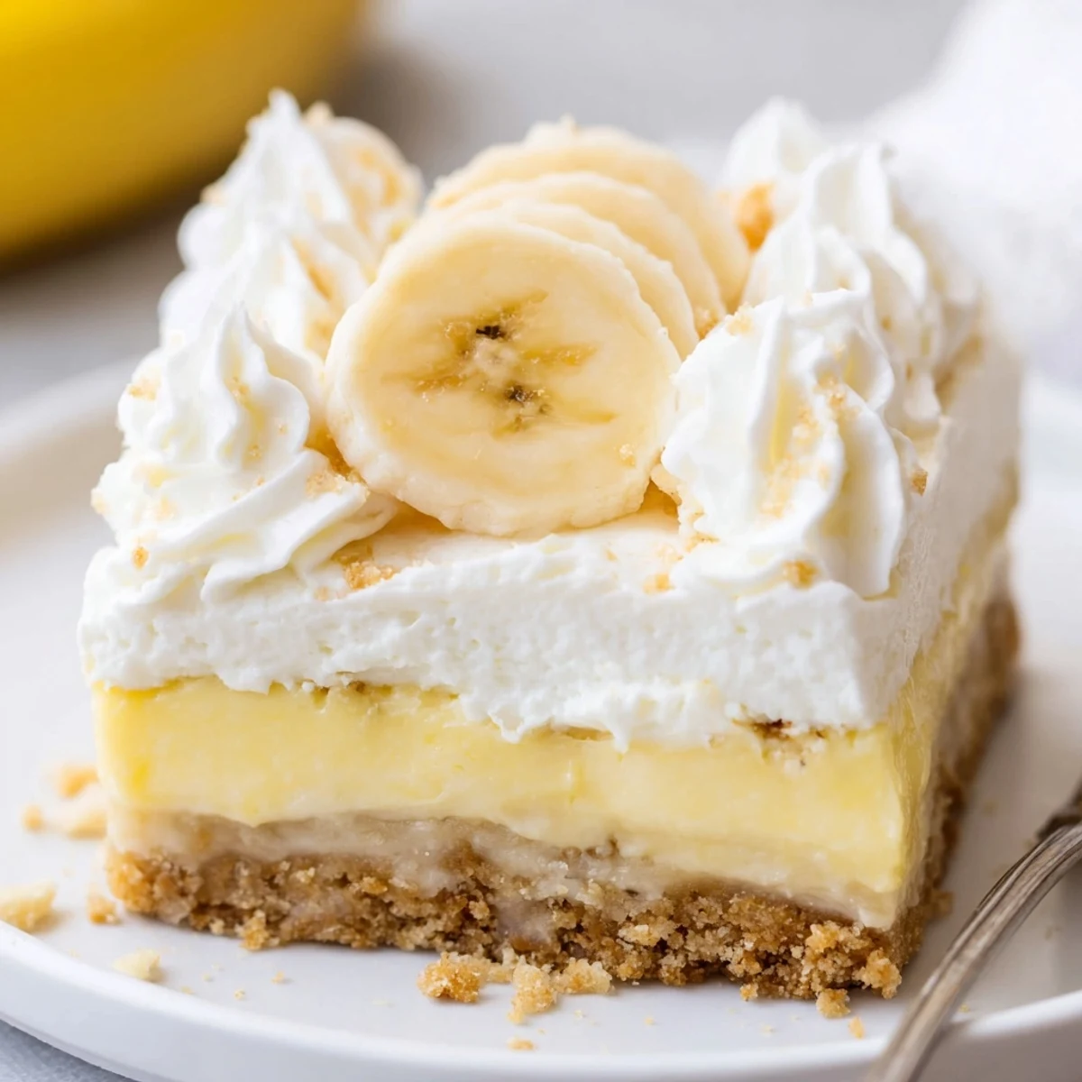 Creamy Banana Pudding Cheesecake Squares topped with whipped cream and banana slices