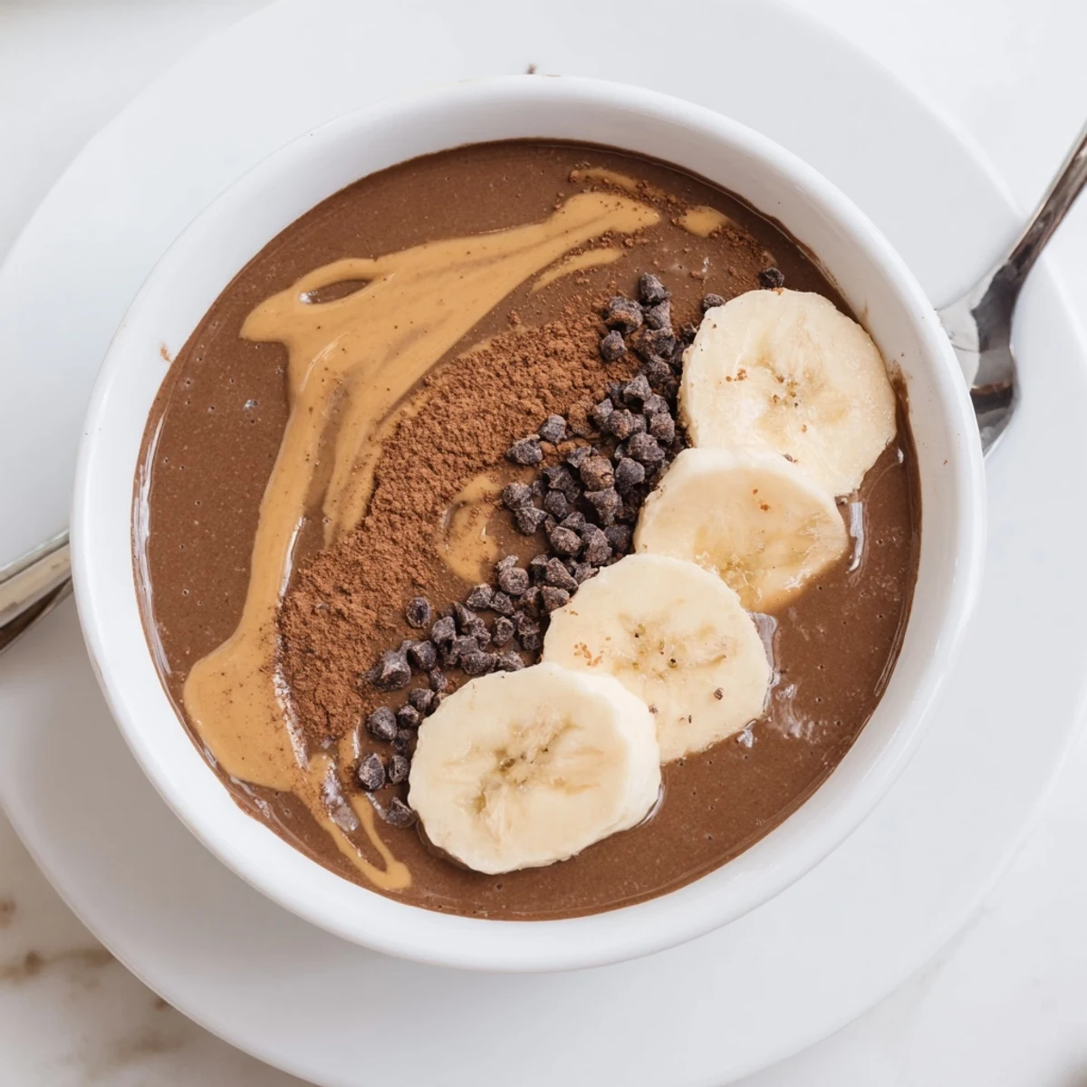 Frothy Chocolate Peanut Butter Protein Smoothie topped with cacao nibs and sliced banana