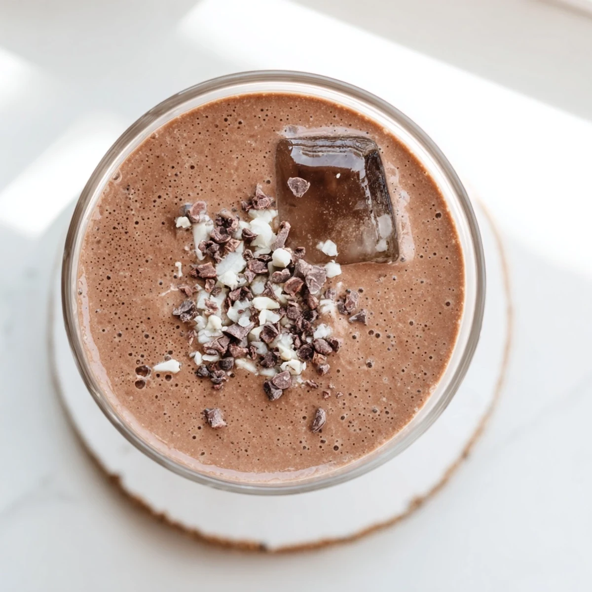 Thick raw chocolate banana shake poured into glasses with frothy chocolate bubbles on top