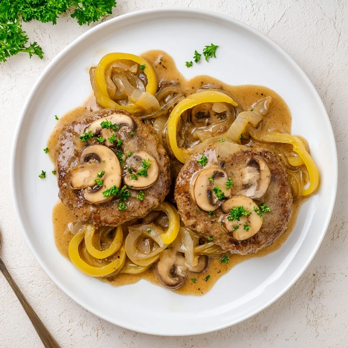 Golden brown Country Style Smothered Cube Steak resting in rich onion mushroom gravy garnished with fresh parsley