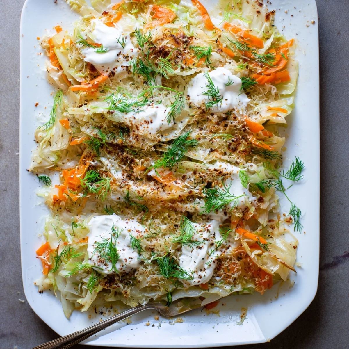 Golden brown slow roasted cabbage and sauerkraut casserole topped with fresh dill and sour cream