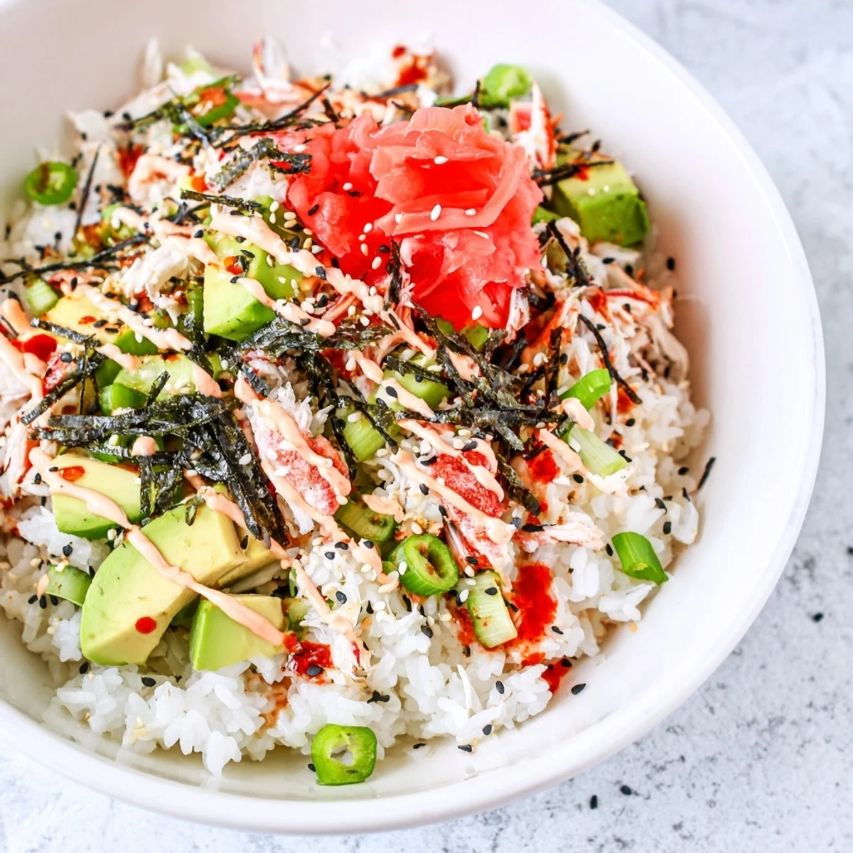 Colorful California roll sushi bowls topped with crab avocado cucumber and drizzled spicy mayo