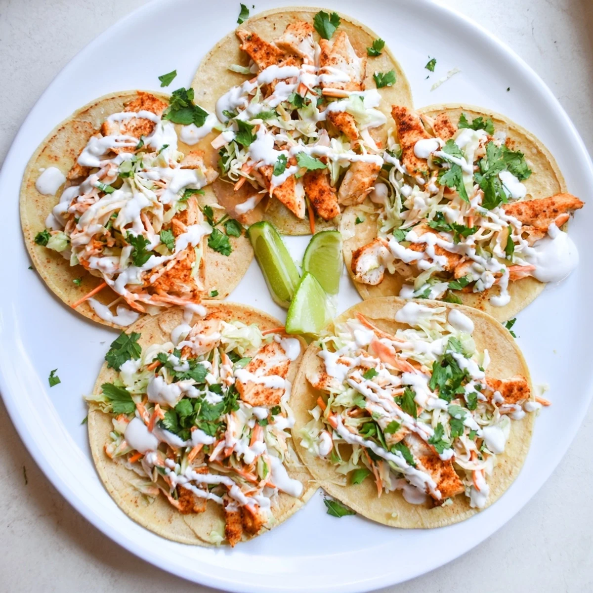 Golden baked cod fish tacos topped with colorful cabbage slaw and creamy lime drizzle
