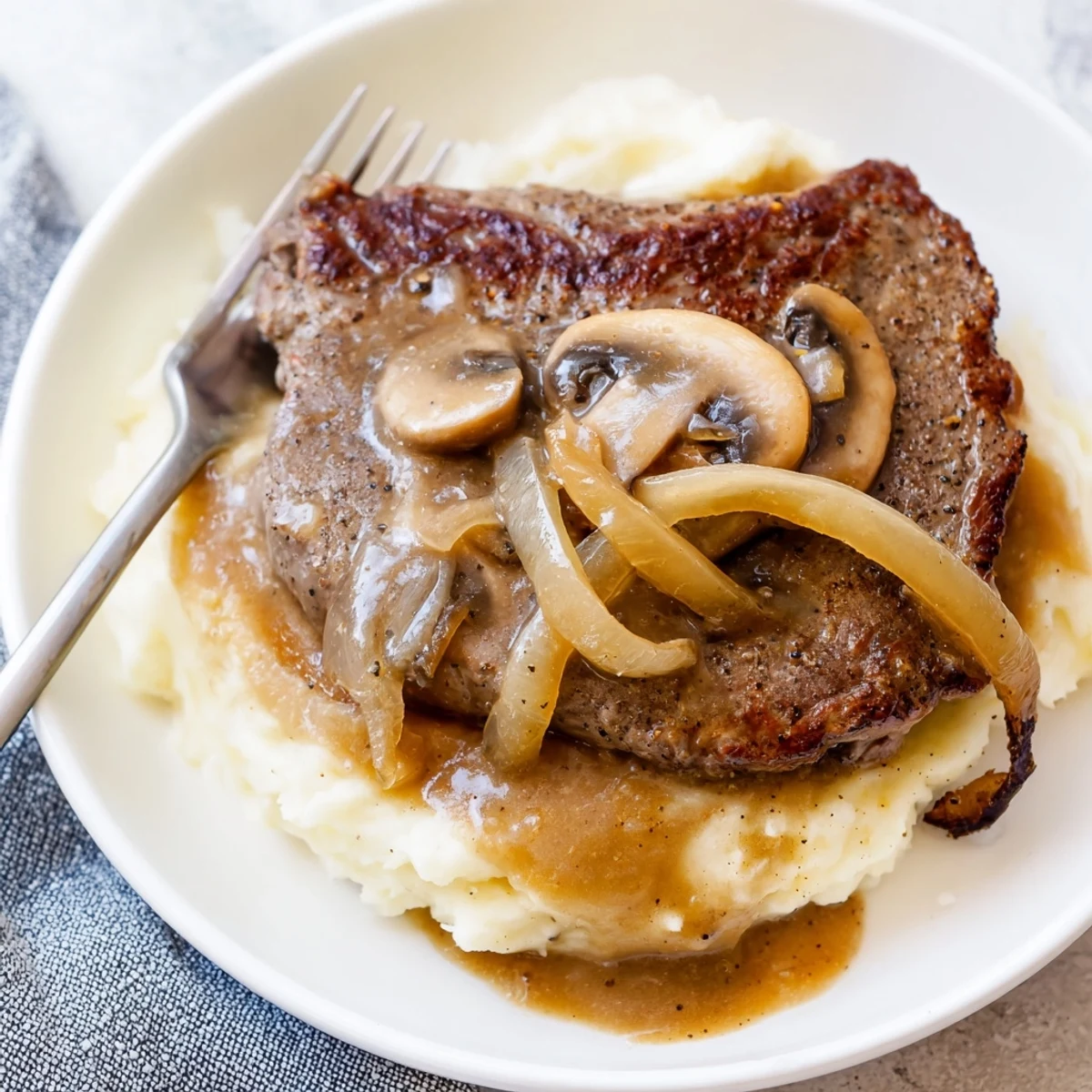 Country Style Smothered Cube Steak Recipe topped with glossy onion and mushroom gravy