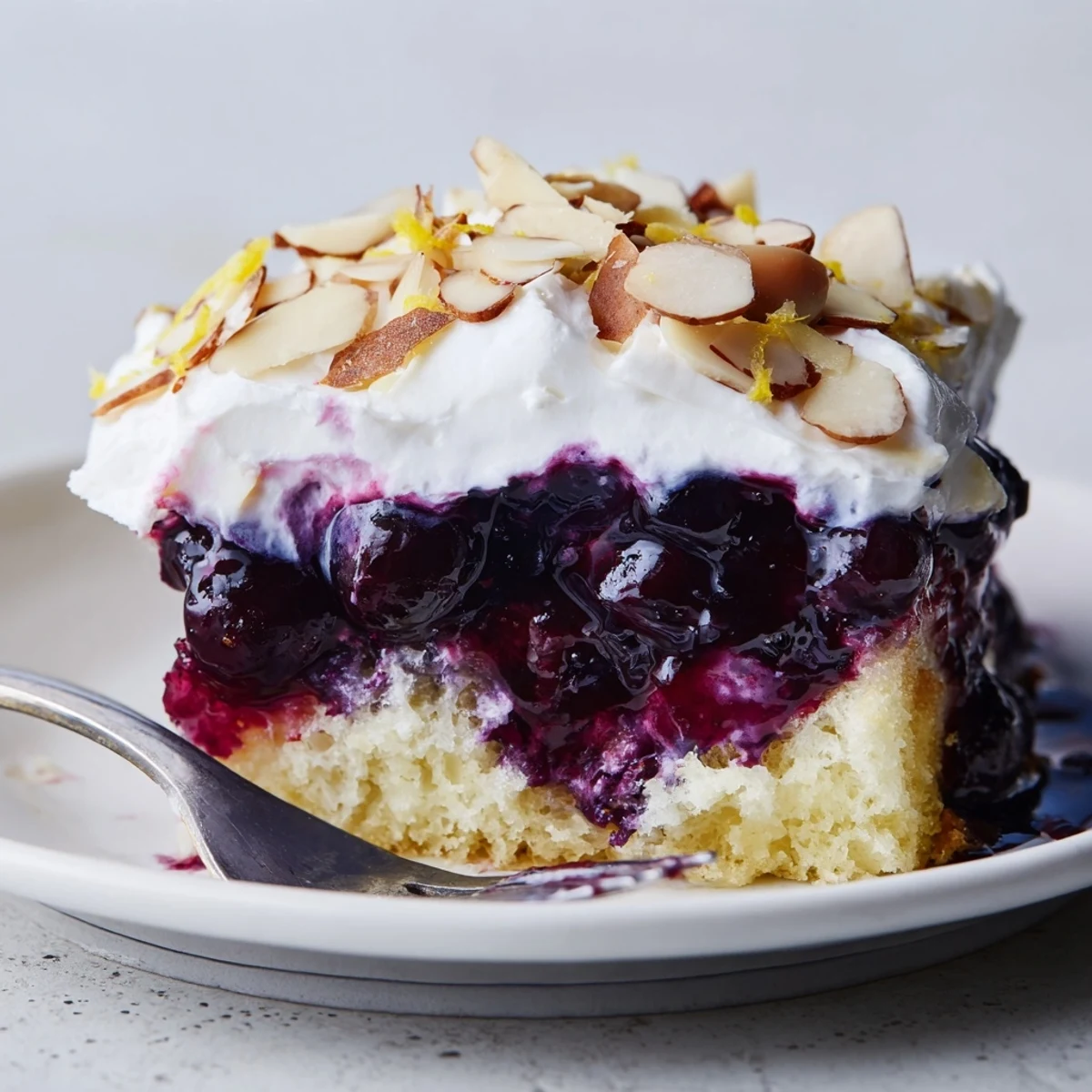 Lemon Blueberry Poke Cake With Almond Topping chilled, dollop of whipped almond cream