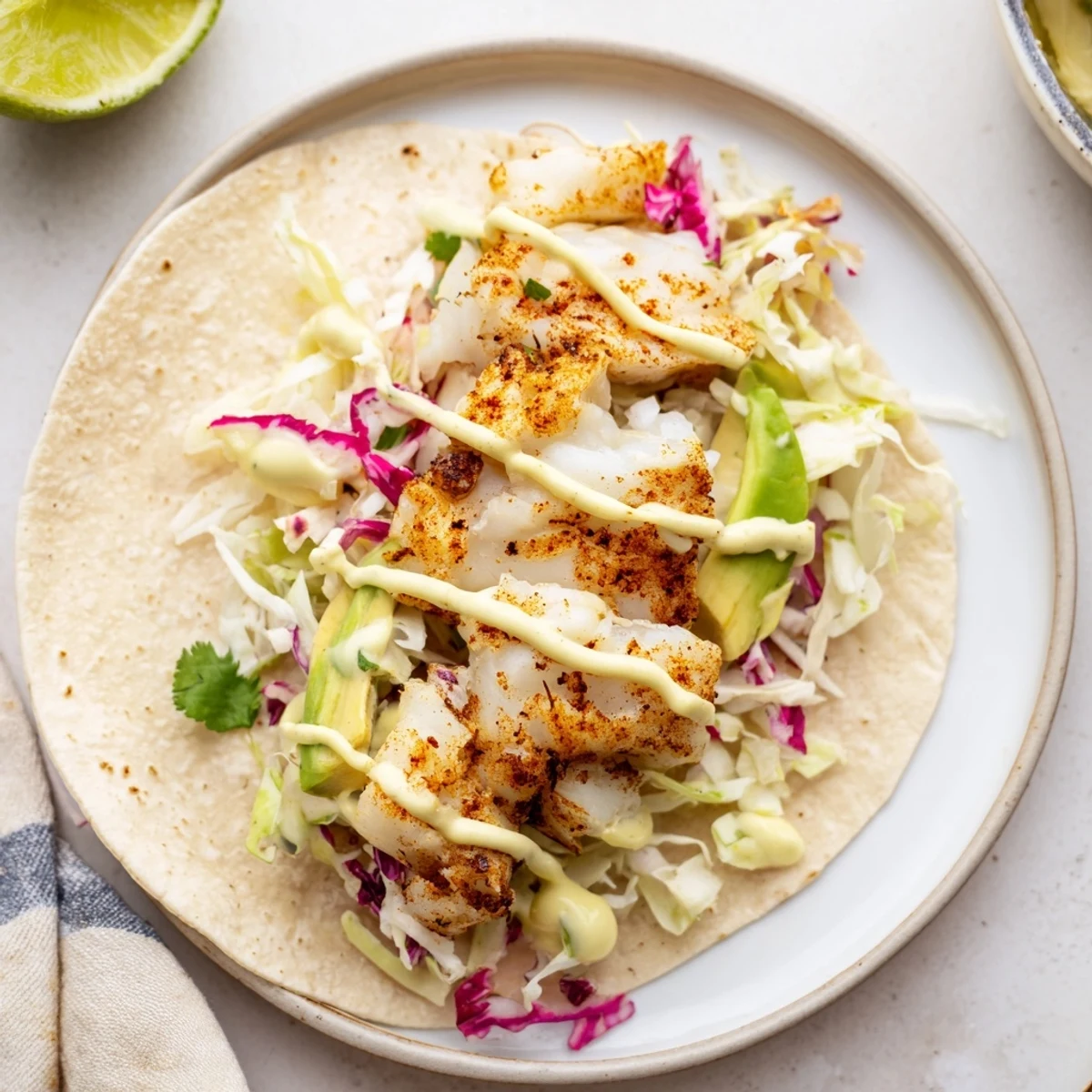 Crisp slaw and avocado top Baked Cod Fish Tacos with Creamy Cilantro Lime Sauce.
