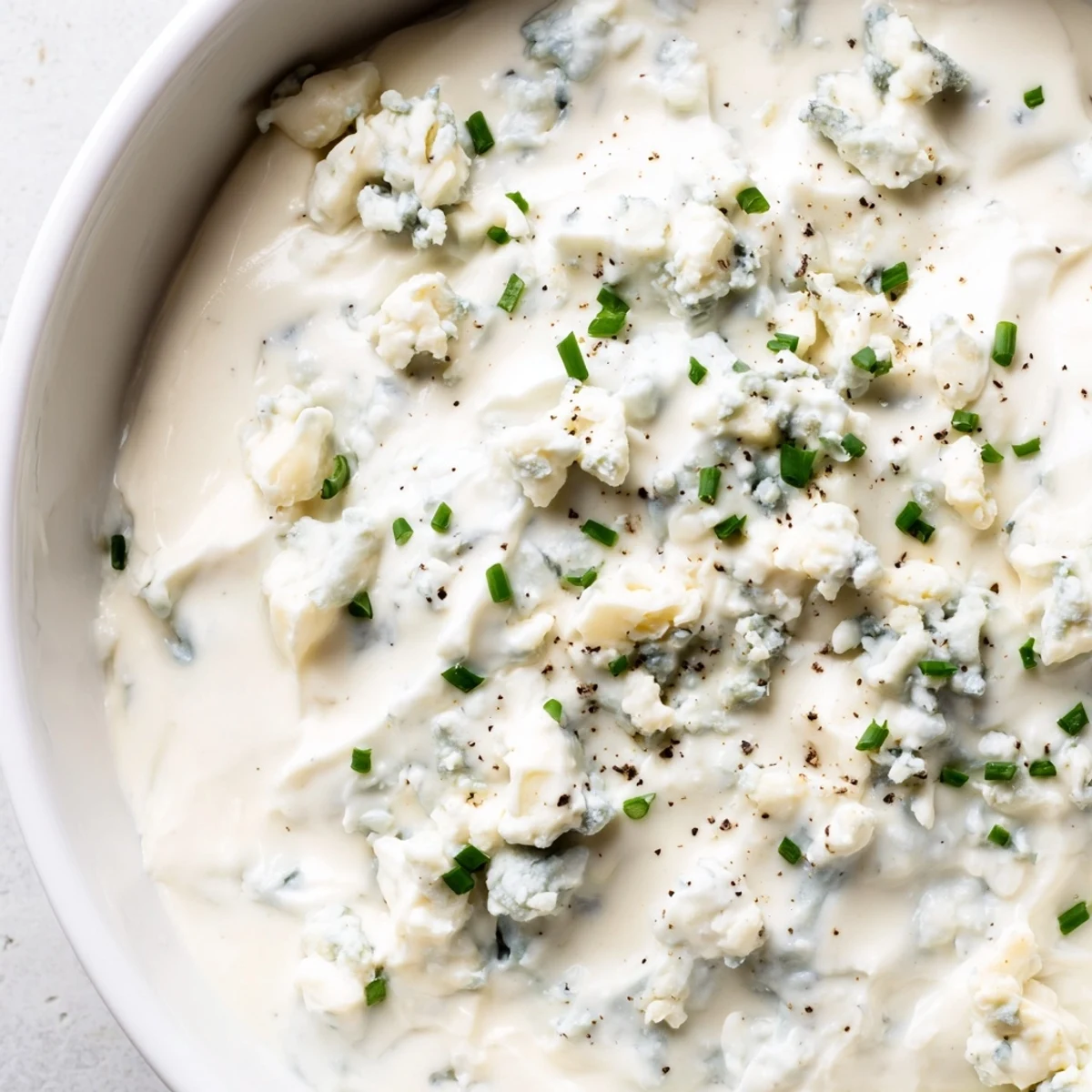 Chunky blue cheese dip topped with chives in a rustic bowl