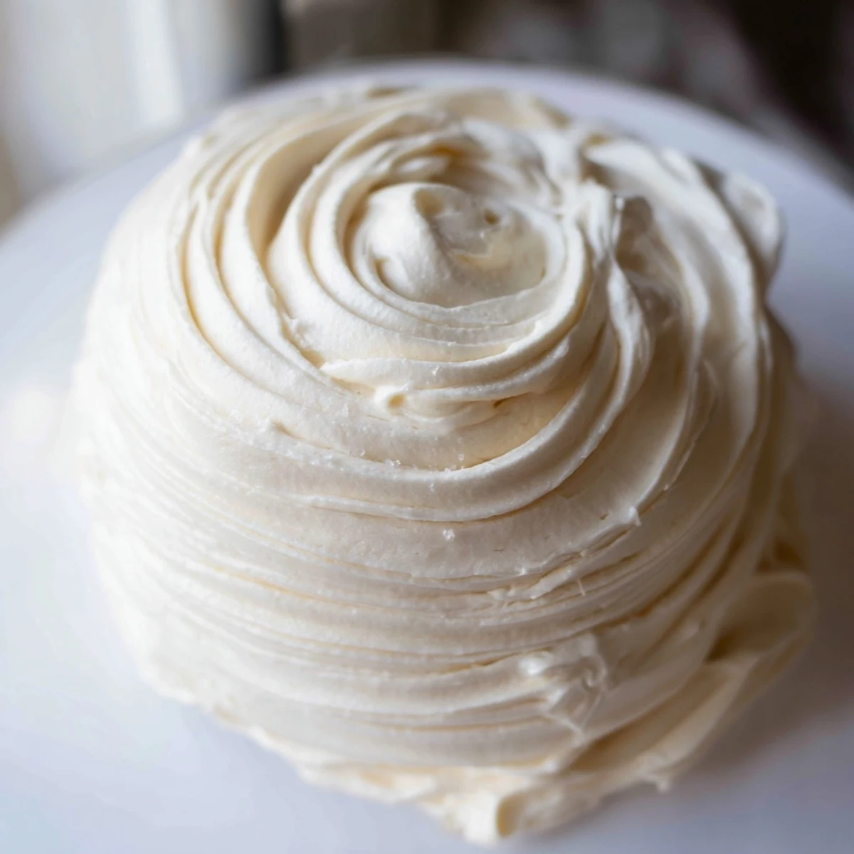 Creamy Italian Meringue Buttercream piled high on a freshly frosted layer cake