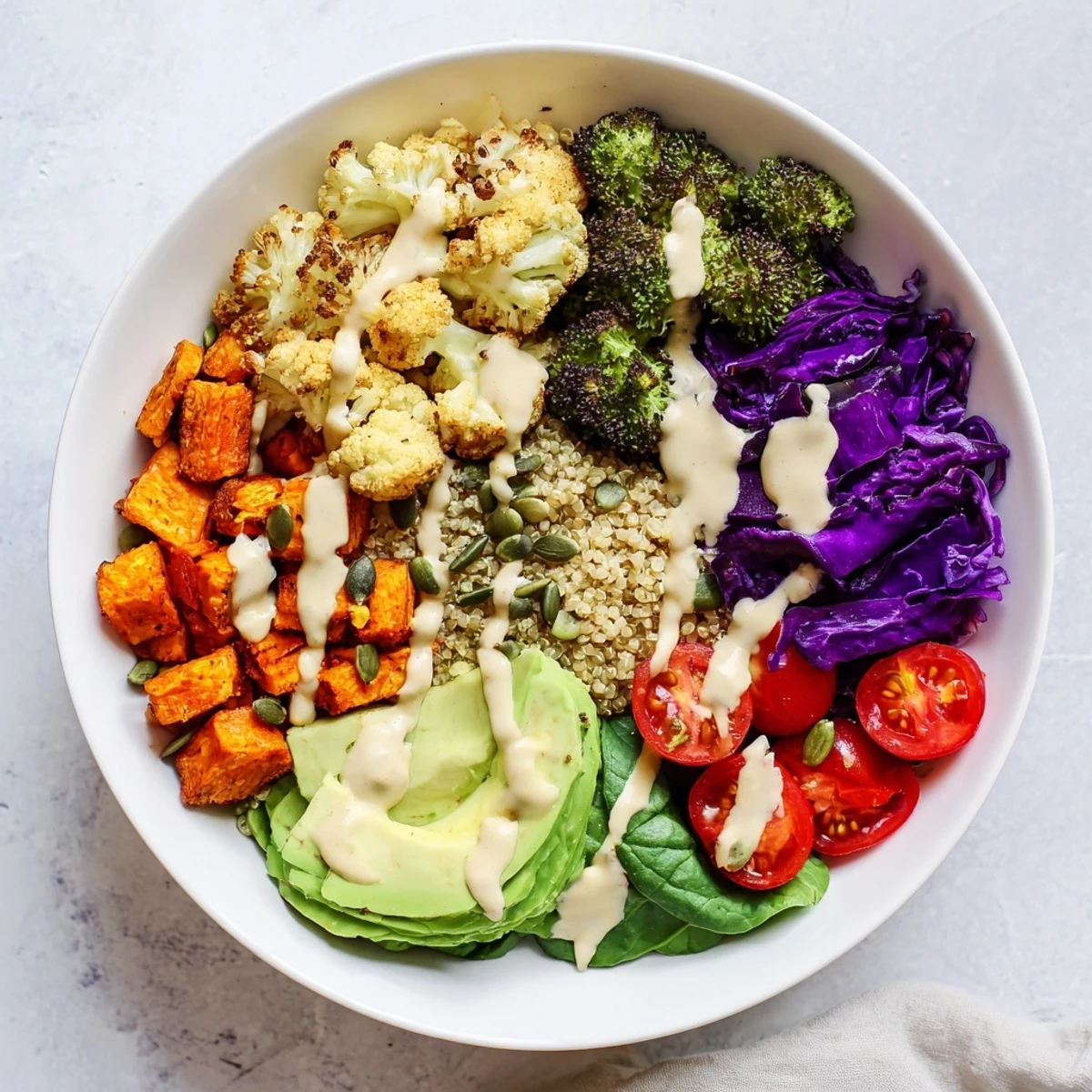 Vegan Buddha Bowl with roasted sweet potatoes, creamy avocado, and golden tahini drizzle over fluffy quinoa