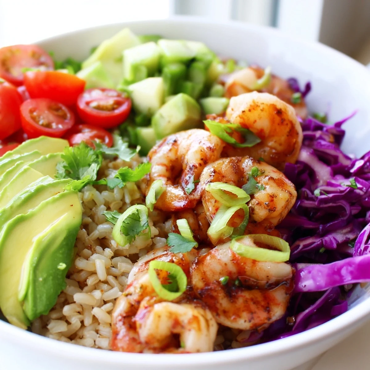 Golden smoked paprika shrimp grain bowl topped with avocado and fresh vegetables