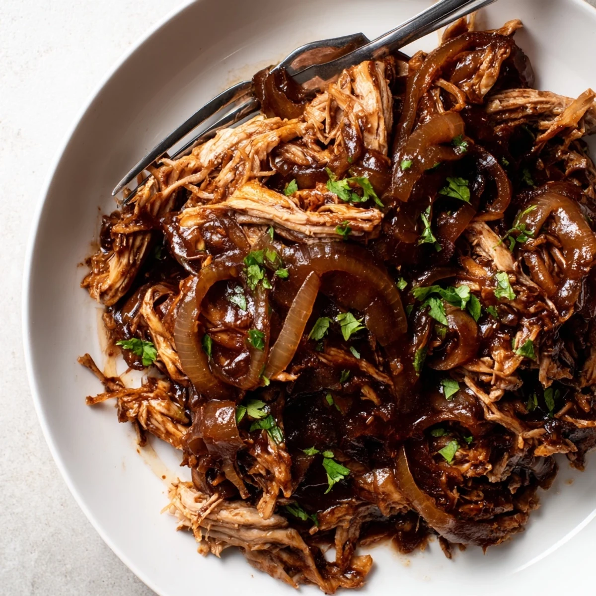 Tender Slow Cooker Balsamic Chicken plated over caramelized onions with fresh parsley garnish