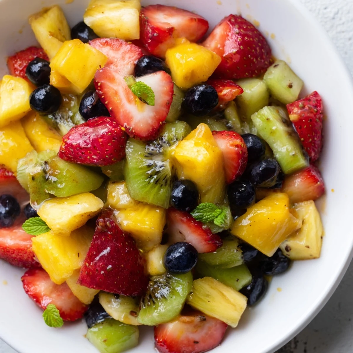 Colorful fruit salad with honey lime dressing served in a rustic white bowl