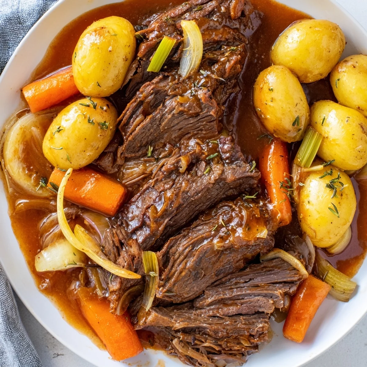 Perfect pot roast sliced thick with fork-tender root vegetables soaking in savory pan juices