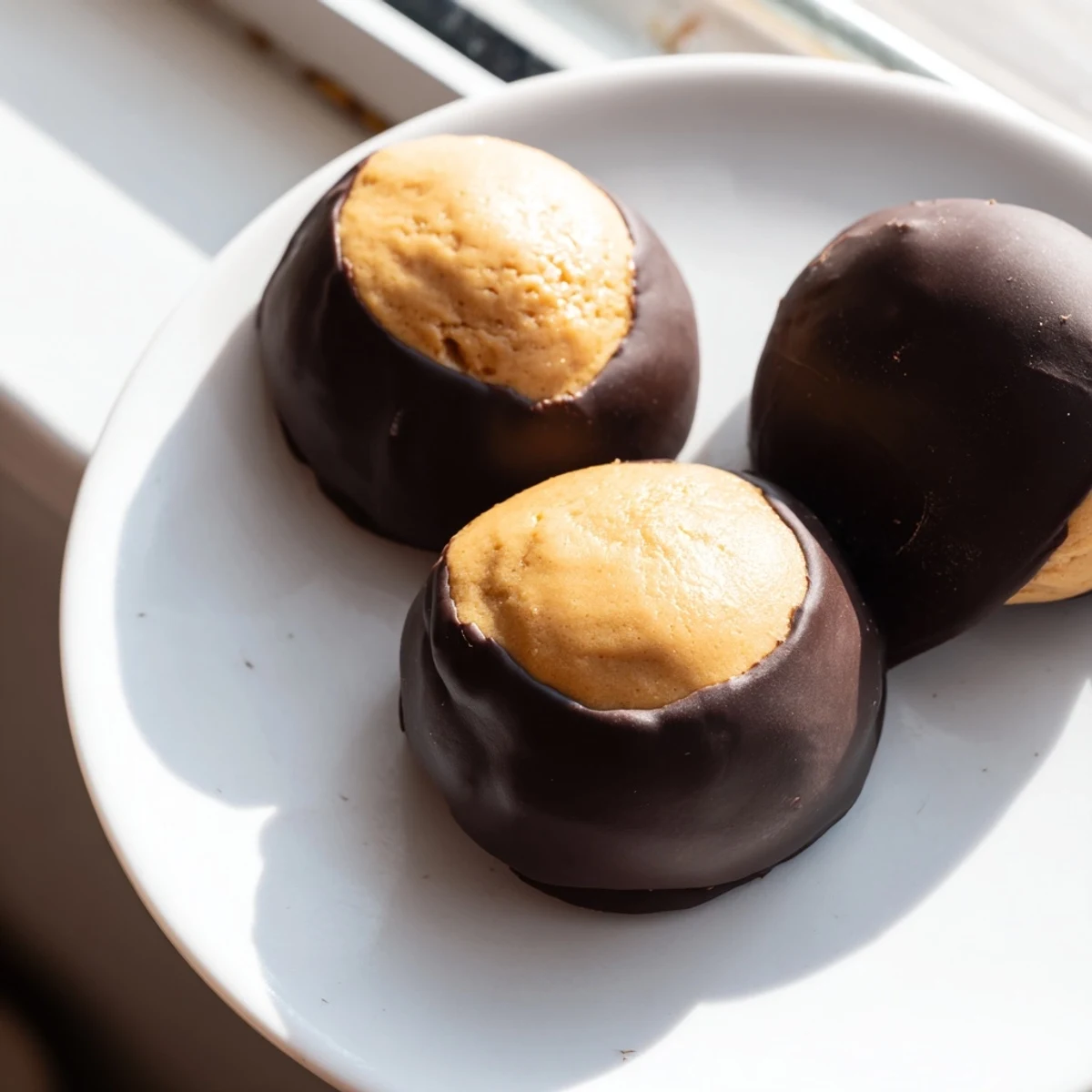Creamy peanut butter buckeye cookies dipped in glossy semisweet chocolate on parchment paper