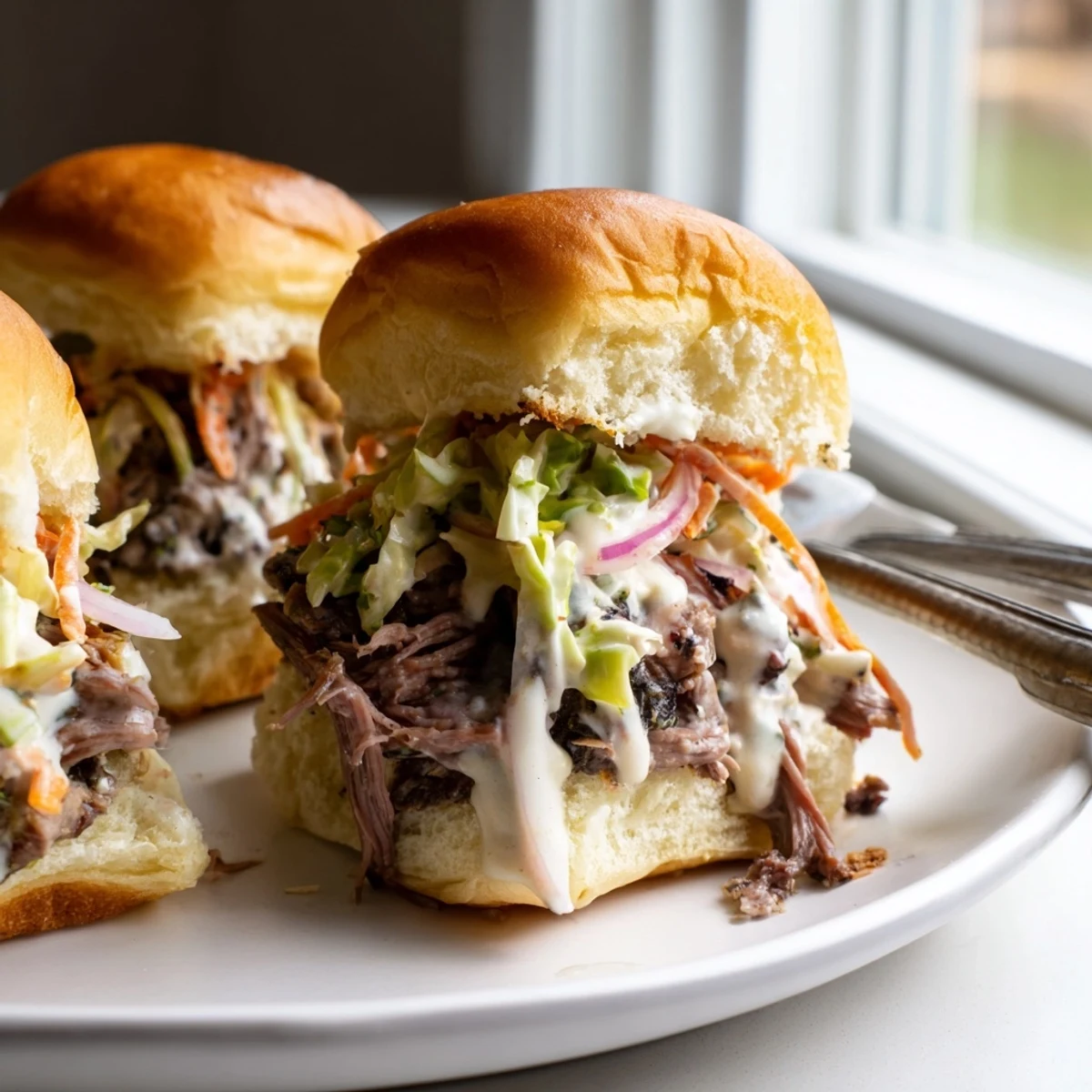 Golden slider buns filled with saucy Alabama white sauce pulled lamb and crisp cabbage slaw