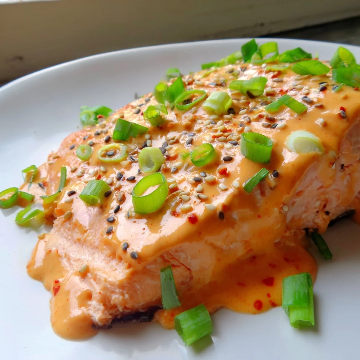 Golden Bang Bang Salmon drizzled with spicy creamy sauce and fresh avocado cucumber salsa