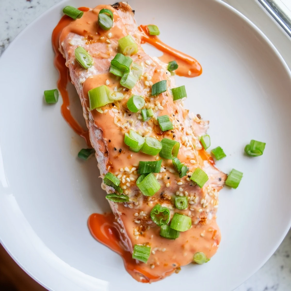 Crispy baked Bang Bang Salmon topped with cool avocado cucumber salsa and sesame seeds