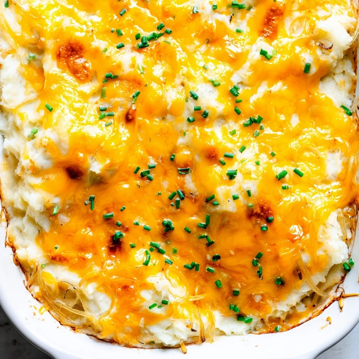 Golden bubbling cheesy onion mashed potato casserole fresh from the oven with crispy edges