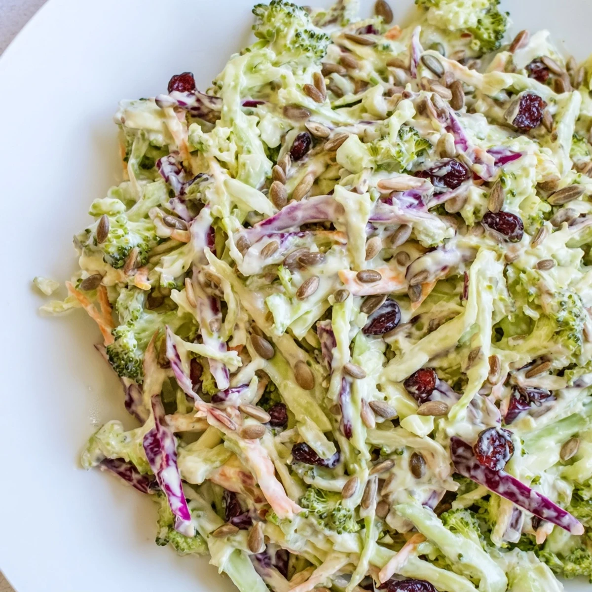 Chilled broccoli slaw served in a bowl with crunchy almonds and sweet dried cranberries