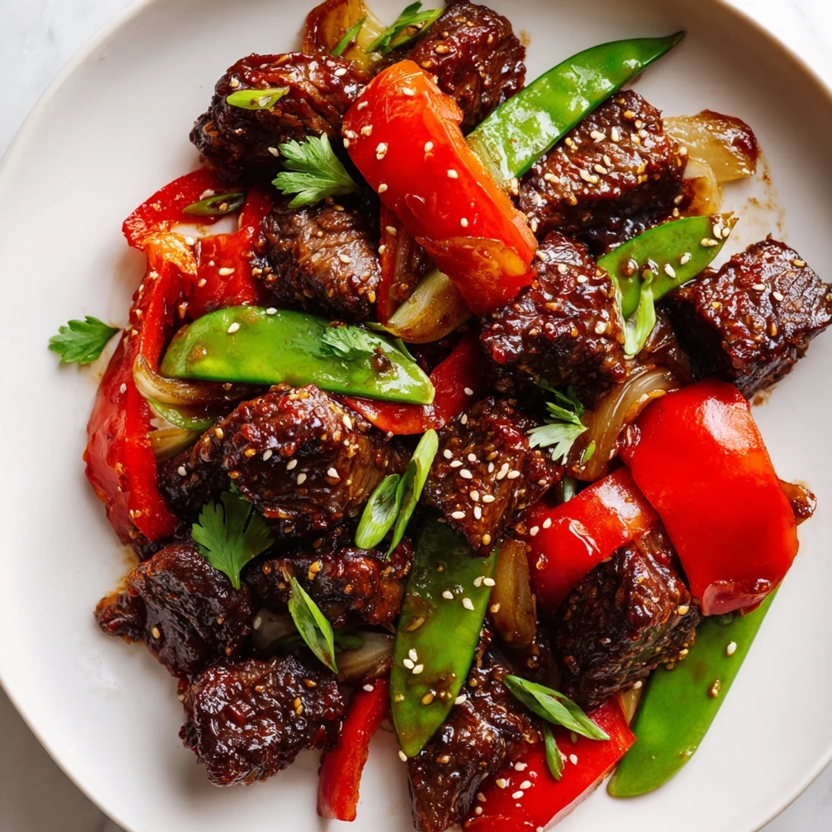 Pan-seared Asian-inspired cube steak topped with sesame seeds beside vibrant bell peppers