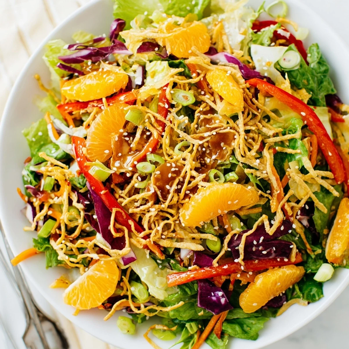Crisp Mandarin Sesame Crunch Salad topped with golden noodles and sweet orange segments
