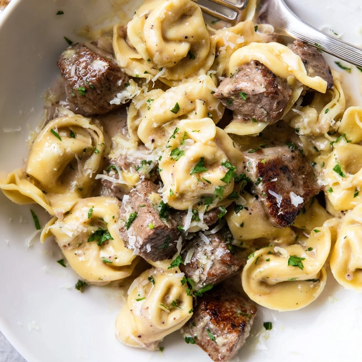 Sizzling steak bites nestled beside plump cheese tortellini drenched in rich garlic cream