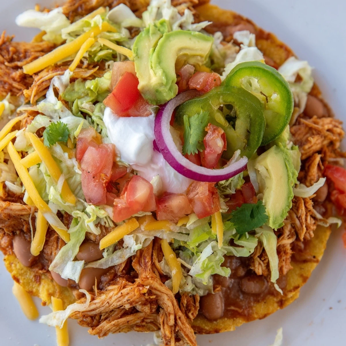 Golden corn tostadas topped with seasoned chicken, lettuce, avocado, and zesty lime wedges  
