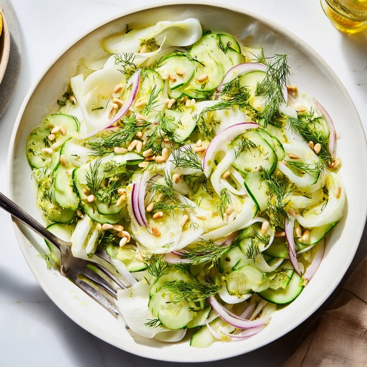 Light Mediterranean crisp fennel cucumber salad garnished with lemon zest and pine nuts