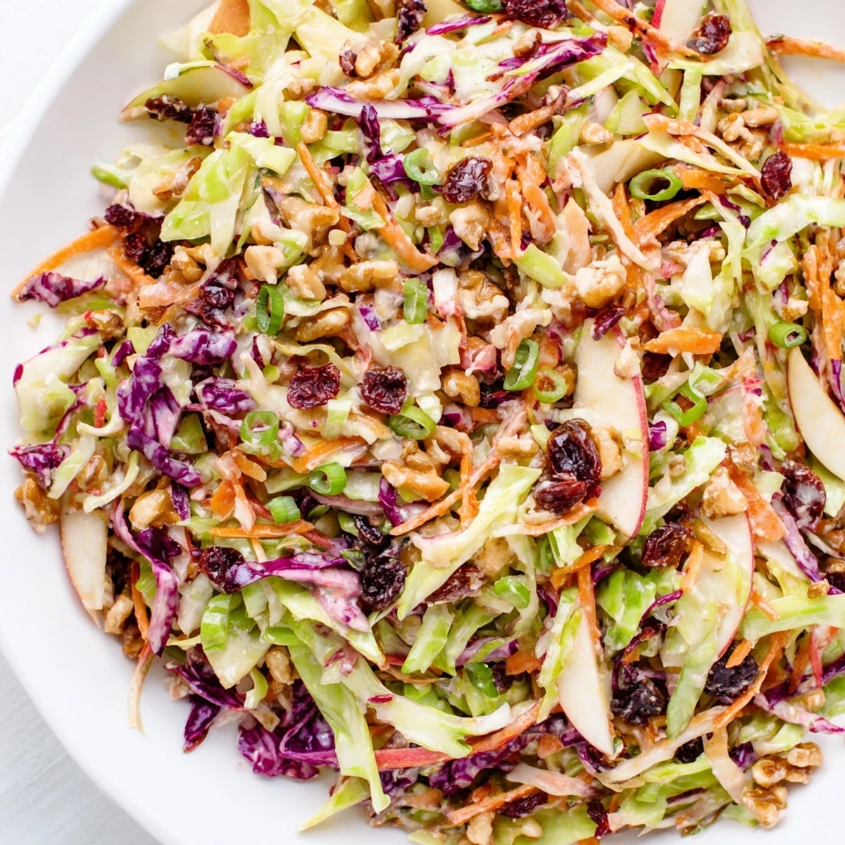 Colorful bowl of cranberry apple coleslaw with shredded cabbage and fresh apple slices.