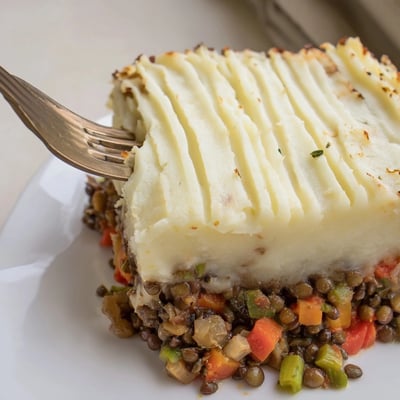 A hearty Lentil &amp; Veggie Shepherds Pie filling with colorful vegetables under creamy potatoes.